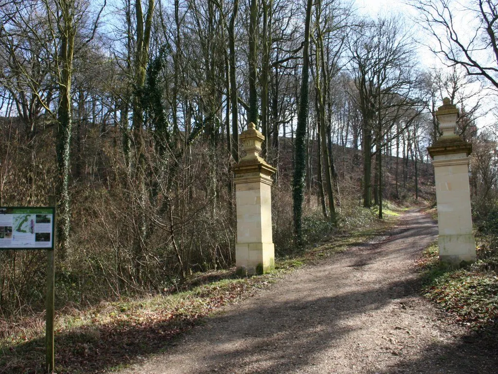 An unpaved road through the woods, with old gate pillars
